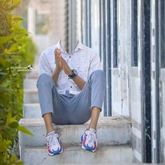 a man sitting on the steps with his hands in his pockets and wearing blue sneakers