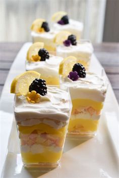 several desserts are arranged on a long white platter with lemon slices and blackberries