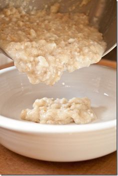 oatmeal being poured into a white bowl on top of a wooden table