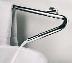 a close up of a faucet in a sink with a towel hanging on the wall