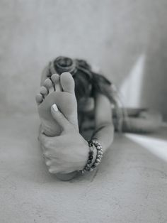 black and white photograph of a woman's foot with her hands on the ground