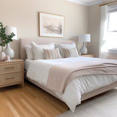 a white bed sitting next to a window in a bedroom on top of a hard wood floor