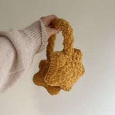 a hand holding a crocheted bag with a knot at the top and bottom