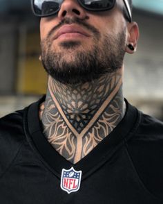 a close up of a man with tattoos on his neck and chest wearing a football jersey