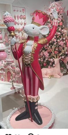 a statue of a mouse in a pink and gold outfit