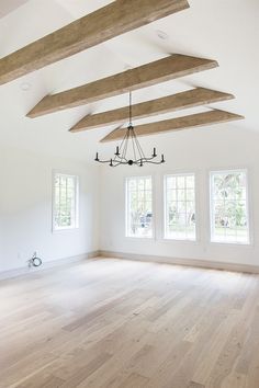 an empty living room with wood floors and exposed beams on the ceiling is pictured in this image