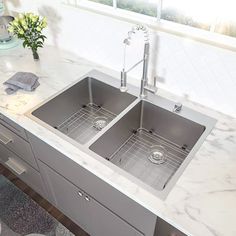 two stainless steel sinks in a kitchen with marble counter tops and gray rug on the floor