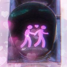 a close up of a traffic light with two people holding hands and hearts in the background