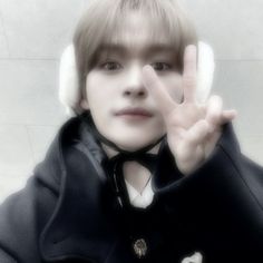 a young boy wearing headphones making the peace sign