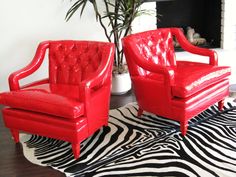 two red leather chairs sitting on top of a zebra print rug in front of a fireplace