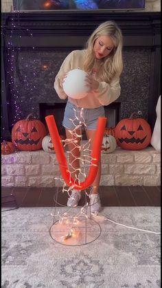 a woman standing in front of a fire place holding a white ball and orange string