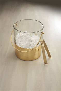 a bucket filled with ice sitting on top of a wooden table next to a pair of scissors