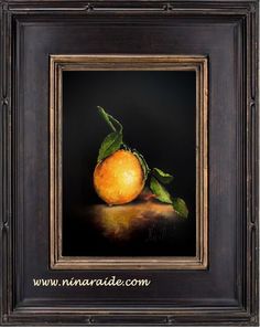 an orange with green leaves on it is in a black frame, against a dark background