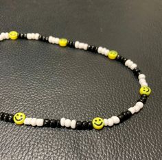 a black and white beaded necklace with yellow smiley face beads on the end of it