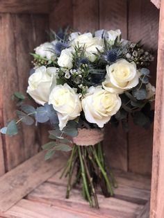 a bouquet of white roses and greenery in a wooden crate