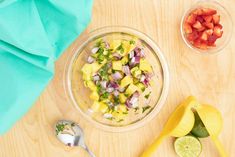 a bowl filled with fruit and vegetables on top of a wooden table next to two spoons