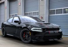 a black dodge charger parked in front of a garage