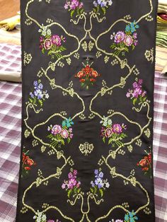 a black cloth with flowers on it sitting on top of a checkered tablecloth