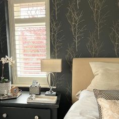 a bedroom with black and white wallpaper, bedding, nightstands and lamp