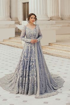 a woman in a blue and white gown standing on the steps of an old building