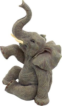 an elephant figurine sitting on the ground with it's trunk in its mouth