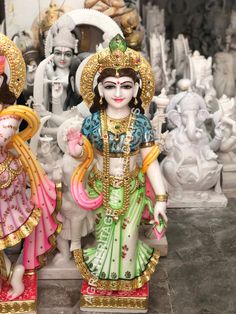 two statues of hindu deities on display in a room with many other statues behind them