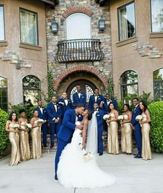 a bride and groom kissing in front of their wedding party at the entrance of a mansion