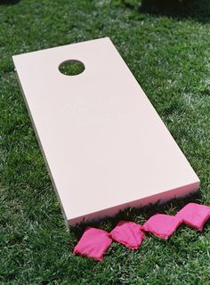 a white board and pink pieces on the grass