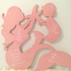 two pink mermaid silhouettes with names on them, one is holding a baby girl