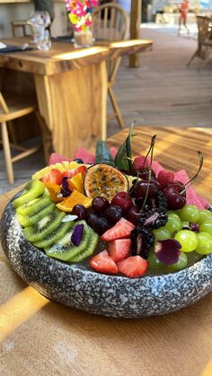 a bowl filled with lots of different types of fruit on top of a wooden table