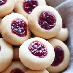 a bunch of cookies with jam on them in a bowl, ready to be eaten