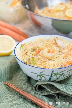 a bowl filled with noodles and carrots next to chopsticks on a table