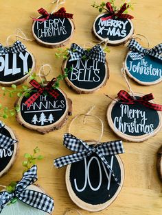 christmas ornaments made out of wood are displayed on a wooden table with greenery and ribbon