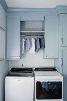 a washer and dryer in a laundry room with blue cabinets on the wall