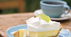 a slice of lemon pie on a plate with a cup of coffee