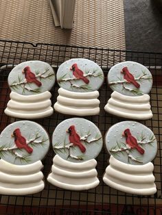 six red birds on white plates sitting on a wire rack