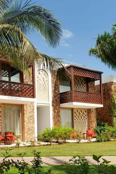 an apartment building with two balconies and palm trees in the front lawn area