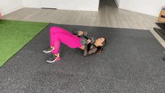 a woman in pink pants and black top doing a push up with dumbbells