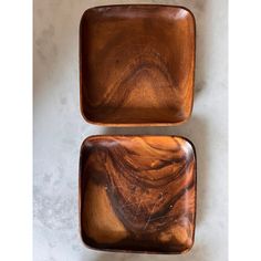 two square wooden plates sitting on top of a white countertop next to each other