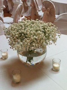 a vase filled with baby's breath sitting on top of a table next to candles