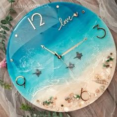 a clock with the word love written on it and sea shells in front of it