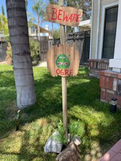 a wooden sign that says beware and ogre on it in front of a house