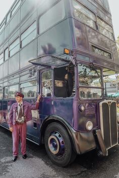 a man standing next to a purple double decker bus