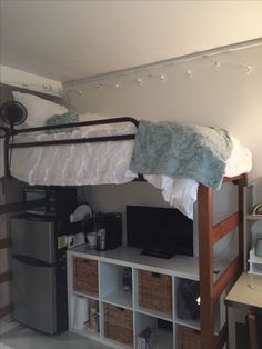 a loft bed with shelves underneath it and a tv on the bottom shelf above it