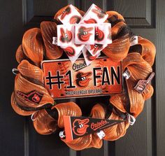 an orange and black wreath with the number 1 fan on it is hanging from a door