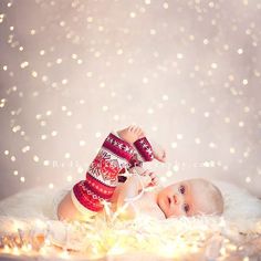 a baby laying on top of a white blanket wearing a red and white christmas sweater