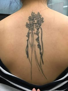 the back of a woman's neck with flowers on her left shoulder and behind her is a drawing of a bride