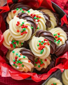 a bowl filled with lots of white and chocolate covered desserts on top of red paper