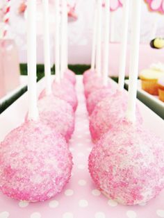 pink cake pops are lined up on a table with polka dot paper and white candles