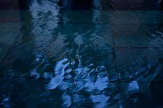 the reflection of two umbrellas in water on a tiled floor with raindrops